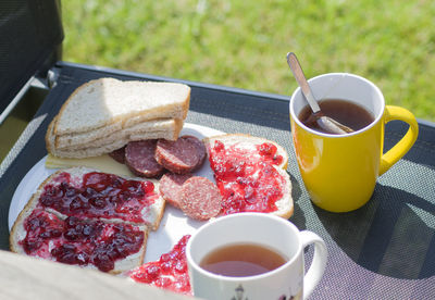 Breakfast in the garden on a chair two sandwiches with sausage and butter jam