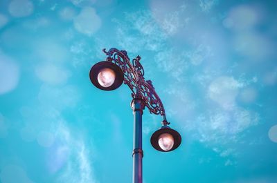 Low angle view of illuminated street light against blue sky