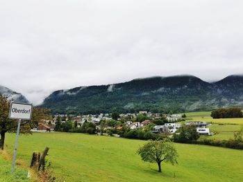 Houses on field by mountains against sky