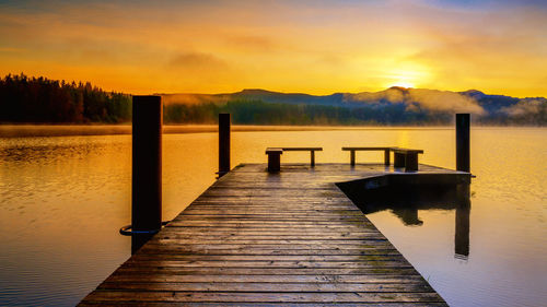 Pier over lake against sky during sunset