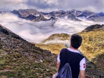 Rear view of man standing on mountain against sky