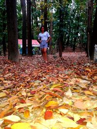 Full length of woman standing in autumn leaves