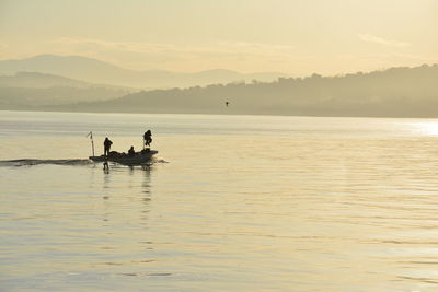 Silhouette people fishing in lake