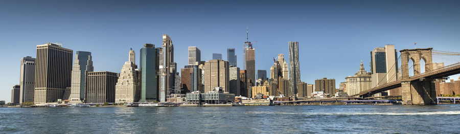 Sea by modern buildings against clear sky