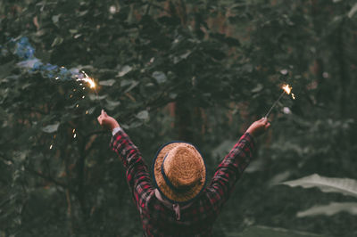 Rear view of woman holding sparklers in forest