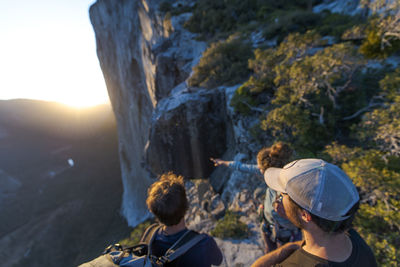 Three hikers looking at the nose el capitan from the top at sunset