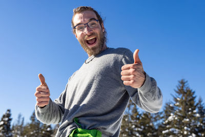 Portrait of smiling young man against blue sky