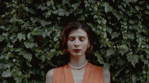 Portrait of young woman standing against plants