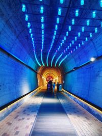 People walking in illuminated tunnel