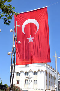 Low angle view of flag against buildings against clear blue sky