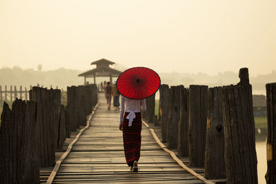 Rear view of woman with traditional umbrella on u bein bridge