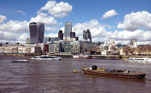 City at waterfront against cloudy sky