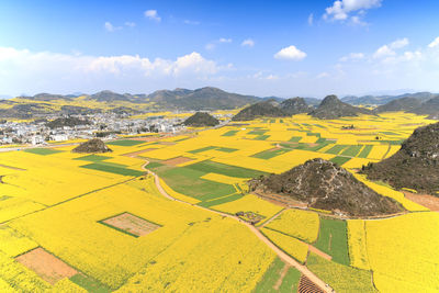 Scenic view of landscape against cloudy sky during sunny day