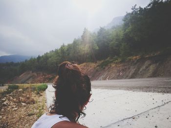 Woman on road by tree against sky