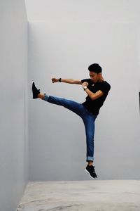 Full length of man kicking while jumping against wall
