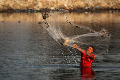 A fisherman is catching fish in a pond on the beach in the afternoon.