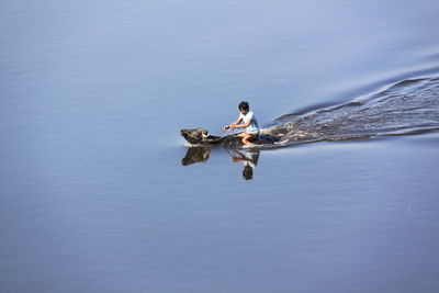 Side view of man sitting on buffalo in water