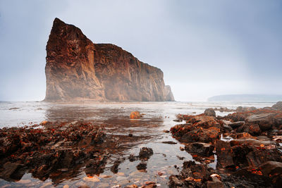 Rock formations on sea shore against sky