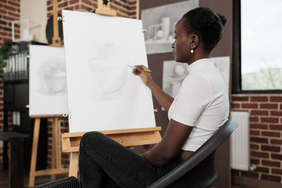 Side view of young woman using digital tablet while sitting at home