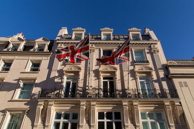 Low angle view of flags in city against clear sky