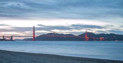 Golden gate bridge over sea against cloudy sky