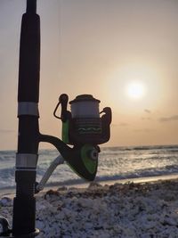 Fire hydrant on beach against sky during sunset