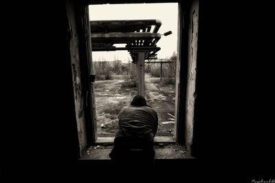 Rear view of man standing by window