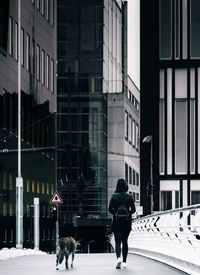 Rear view of man walking against building in city