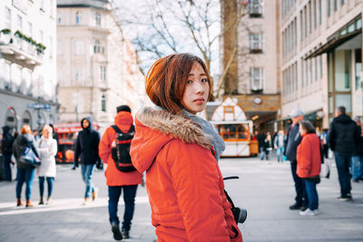 Portrait of woman standing on footpath in city during winter