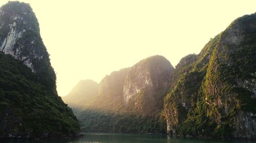 Scenic view of river by mountains against clear sky