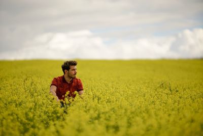 Man sitting on field against sky