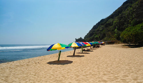 Deck chairs on beach against clear sky