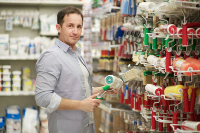 Portrait of man buying paint roller in store