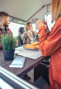 Friends having breakfast in a camper van in the morning