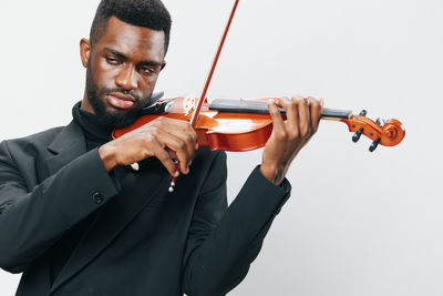 Midsection of man holding violin against white background