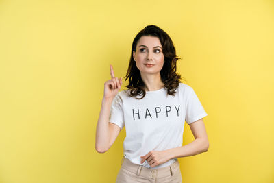 Portrait of woman standing against yellow background