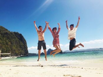 Full length of young couple jumping on beach