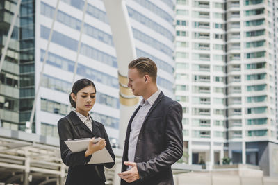 Low angle view of business people discussing while standing against building