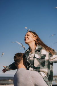 Man and woman wearing mask against sky