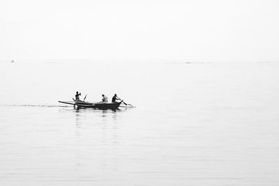 People on boat sailing in sea against clear sky