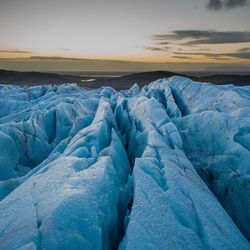 Scenic view of frozen landscape against sky during sunset