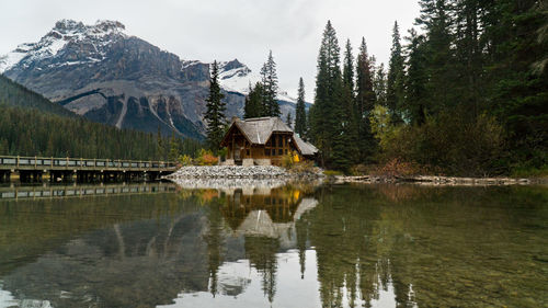 Reflection of house and trees in lake against sky