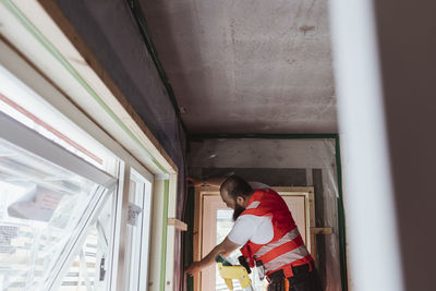 Male construction worker measuring wall while working at site