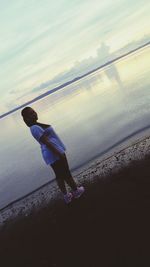 Full length of child on beach against sky during sunset