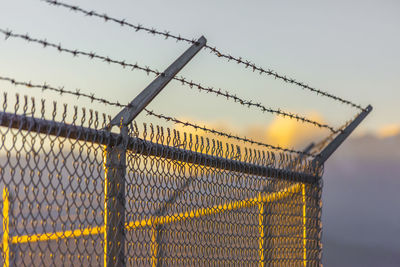 Close-up of barbed wire fence against sky