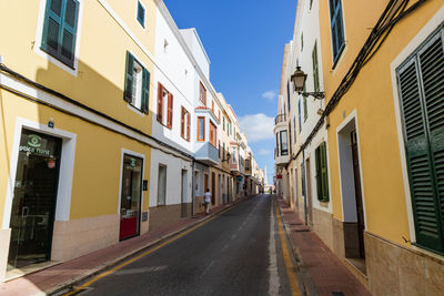 Empty road amidst buildings against sky