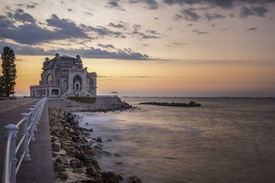 Scenic view of sea by building against sky during sunset