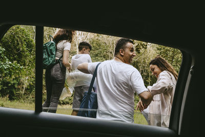 Smiling family seen from electric car in forest during vacation