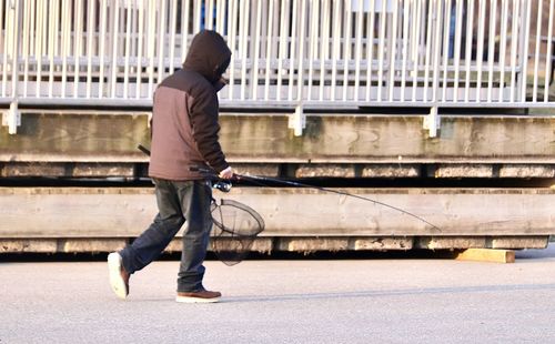 Rear view of man walking on railing in city