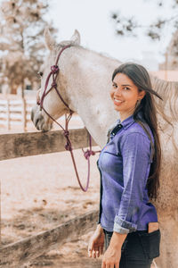 Smiling young woman with horse at ranch